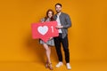 Excited young couple man woman posing with like sign isolated on orange background. Mock up copy space.