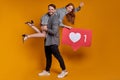 Excited young couple man woman posing with like sign isolated on orange background. Mock up copy space.