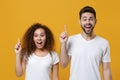 Excited young couple two friends european guy african american girl in white t-shirts posing isolated on yellow wall Royalty Free Stock Photo