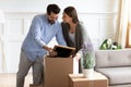 Excited young couple unpack boxes settle at new home