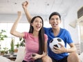 Excited Young couple watching tv and  raising hands to celebrating the victory Royalty Free Stock Photo