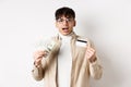 Excited young guy showing dollar bills and credit card, earn money and looking amazed, standing on white background Royalty Free Stock Photo