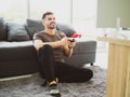 Excited young handsome man playing video game and keeping mouth open while sitting on the couch at home Royalty Free Stock Photo