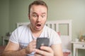 Excited young man with big eyes watching at his phone. Feelling astonished Royalty Free Stock Photo