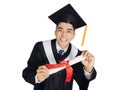 Excited young man in  black graduation gown and cap  showing diploma Royalty Free Stock Photo