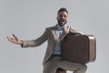 Excited young man holding arm on suitcase and presenting to side Royalty Free Stock Photo