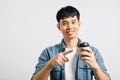 An excited young man holds a takeaway coffee cup, pointing with optimism Royalty Free Stock Photo