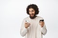 Excited young man looking at mobile phone screen, holding credit card, paying online, shopping in application, white