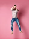 Excited young man in popular shirt jumping celebrating success pointing fingers up over pink Royalty Free Stock Photo