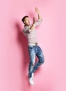 Excited young man in popular shirt jumping celebrating success pointing hands up over pink Royalty Free Stock Photo