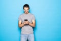 Excited young man posing isolated over blue wall background using mobile phone chatting Royalty Free Stock Photo