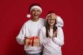 Excited Young Man In Santa Hat Covering Girlfriend's Eyes And Giving Gift