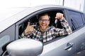 Excited young man showing a car key, sitting inside his new vehicle Royalty Free Stock Photo