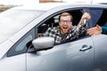 Excited young man showing a car key, sitting inside his new vehicle Royalty Free Stock Photo