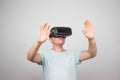 Excited young man using a VR headset and experiencing virtual reality isolated on gray background