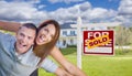 Excited Young Military Couple In Front of Home with Sold Sign