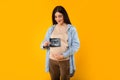 Excited young pregnant woman embracing belly and showing ultrasound picture of unborn baby on yellow backgorund Royalty Free Stock Photo