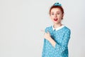 Excited young redhead caucasian girl with hair knot pointing her index finger sideways, raising eyebrows