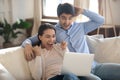 Excited young spouses football fans watching soccer match using laptop