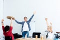 excited young start up team raising hands and looking at pizza boxes