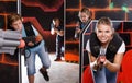 Excited young woman aiming laser gun near other players during laser tag game Royalty Free Stock Photo