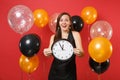Excited young woman in black dress celebrating holding round clock on bright red background air balloon. Time is running Royalty Free Stock Photo