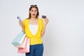 Excited young woman carrying shopping bags with using credit card and mobile phone standing isolated on white background Royalty Free Stock Photo