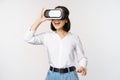 Excited young woman enter virtual reality in her glasses. Asian girl using vr headset, standing over white background Royalty Free Stock Photo