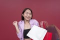 An excited young woman giddy while holding all her shopping bags. Splurging on a shopping extravaganza. Studio shot with burgundy Royalty Free Stock Photo