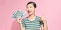 Excited young woman girl posing isolated on pink background studio portrait. Hold fan of cash money in dollar banknotes Royalty Free Stock Photo