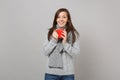 Excited young woman in gray sweater, scarf holding red cup of coffee or tea isolated on grey wall background. Healthy Royalty Free Stock Photo