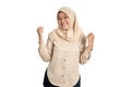 Excited young woman in hijab clenching hands while celebrating success