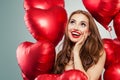 Excited young woman holding balloons red heart. Surprised girl with red lips makeup, long curly hair and cute smile Royalty Free Stock Photo