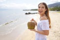 Excited young woman holding green coconut on tropical beach. Summer vacation concept Royalty Free Stock Photo