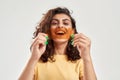 Excited young woman holding orange film in front of her mouth, posing isolated over light background