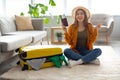 Excited young woman holding passport and ticket near bright packed suitcase at home