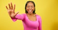 Excited young woman holds up hand, high five close up, yellow studio shoot