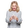 Excited young woman looking at her mobile phone smiling. Woman reading text message on her phone, isolated over white background.