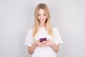Excited young woman looking at her mobile phone smiling. Woman reading text message on her phone  isolated over white background Royalty Free Stock Photo