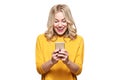 Excited young woman looking at her mobile phone smiling. Woman reading text message on her phone, isolated over white. Royalty Free Stock Photo