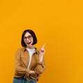 Excited young woman pointing finger up at copy space and looking at camera isolated over yellow background Royalty Free Stock Photo