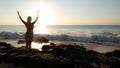 Excited young woman raising arms at the beach in front of the ocean. View from back. Sunset at the beach. Bali, Indonesia Royalty Free Stock Photo