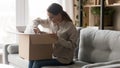 Happy young woman unpacking cardboard box at home Royalty Free Stock Photo