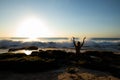 Excited young woman raising arms at the beach in front of the ocean. View from back. Sunset at the beach. Bali, Indonesia Royalty Free Stock Photo