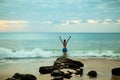 Excited young woman raising arms at the beach in front of the ocean. View from back. Sunset at the beach. Bali, Indonesia Royalty Free Stock Photo