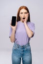 Excited young woman wearing stylish casual clothes holding cell phone with black empty mobile screen Royalty Free Stock Photo