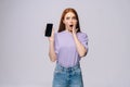 Excited young woman wearing stylish casual clothes holding cell phone with black empty mobile screen Royalty Free Stock Photo