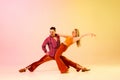 Excitement. Artistic, expressive couple, man and woman emotionally dancing disco dance against gradient pink yellow