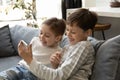 Excites cheerful gen Z little children using smartphone together Royalty Free Stock Photo