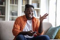 Exciting african american guy sitting at home, watching tv